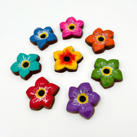 8 chocolate forget-me-not flowers in vibrant blue, pink, orange, green, purple, red, turquoise and yellow, all with black centre.