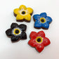 8 chocolate forget-me-not flowers in bold black, red, blue and yellow, all with black and yellow centre.