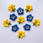 Lily flower in classic yellow, green and black. Pictured with blue forget-me-not flowers. All made from chocolate.