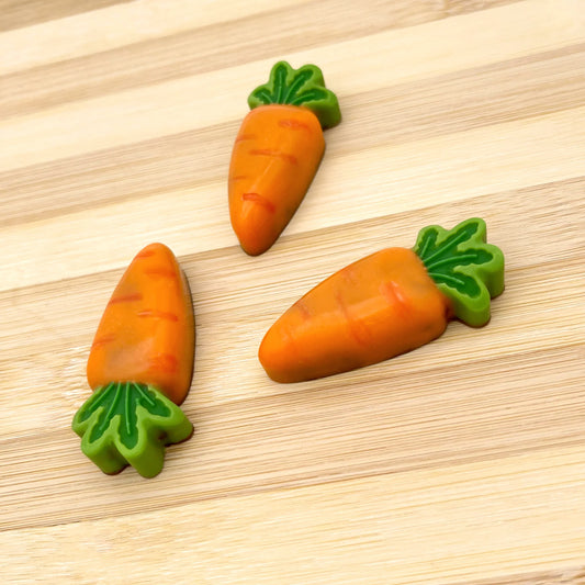 3 realistic-looking baby carrots, coloured in oranges with a green leafy top, all made from chocolate.