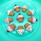 Little cupcakes made from chocolate, decorated with sprinkles, stars and dots on white icing, in beige cups.