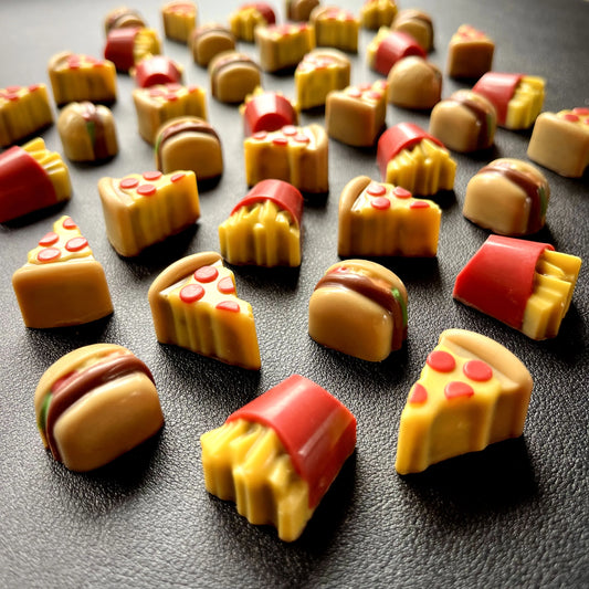 Realistic-looking brightly-coloured pizza slices, burgers and fries in a box, all made from chocolate.