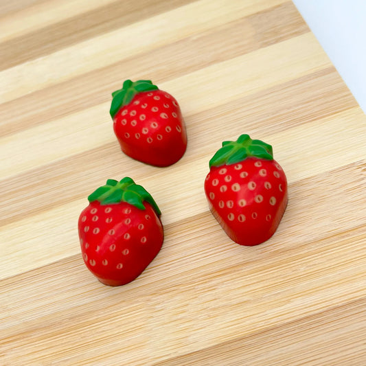 Red chocolate strawberry with green leaves and beige-coloured seeds.