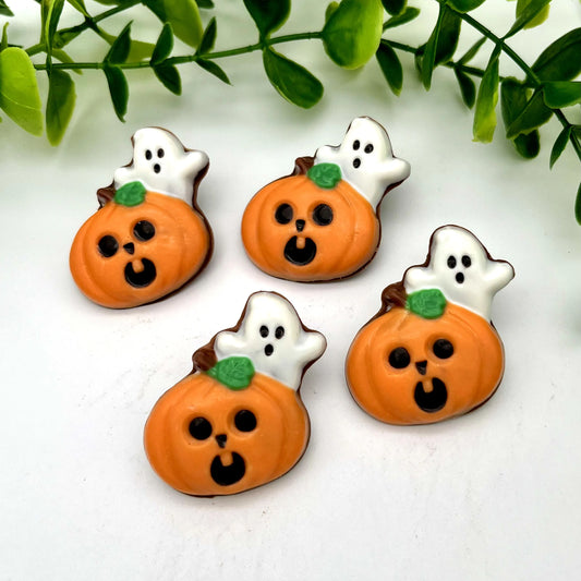Four orange chocolate pumpkins with carved faces, with little ghosts peeking out from behind.