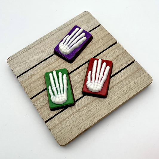 White skeleton hands on a red, purple or green coloured rectangle, all made from chocolate. 