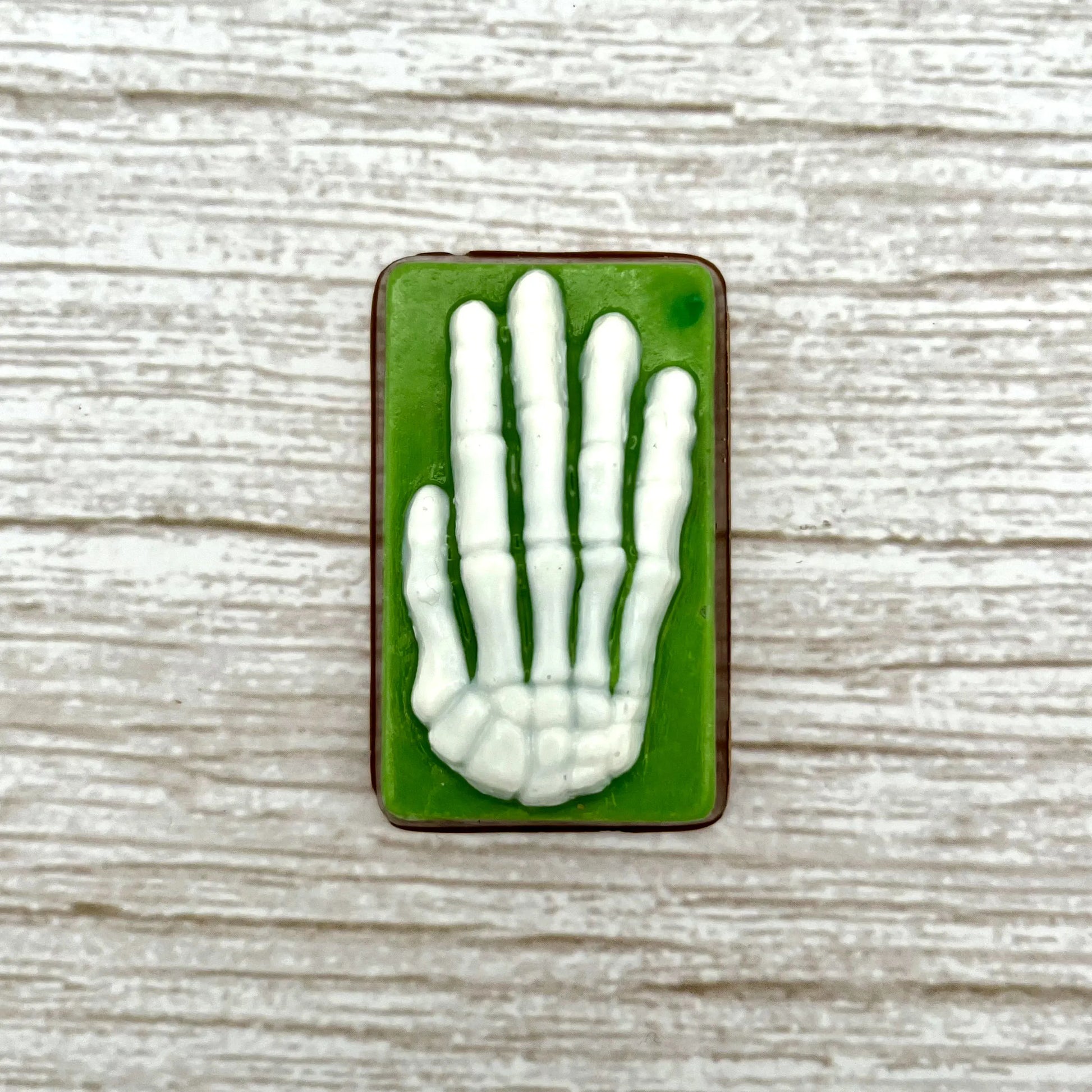 White skeleton hand on a green coloured rectangle, made from chocolate. 