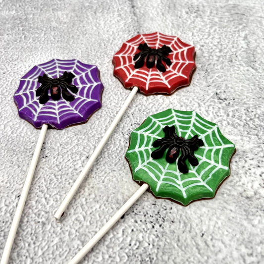 Black widow spider atop a white web, on a red, green or purple background shaped like a web. All made of chocolate as suckers.