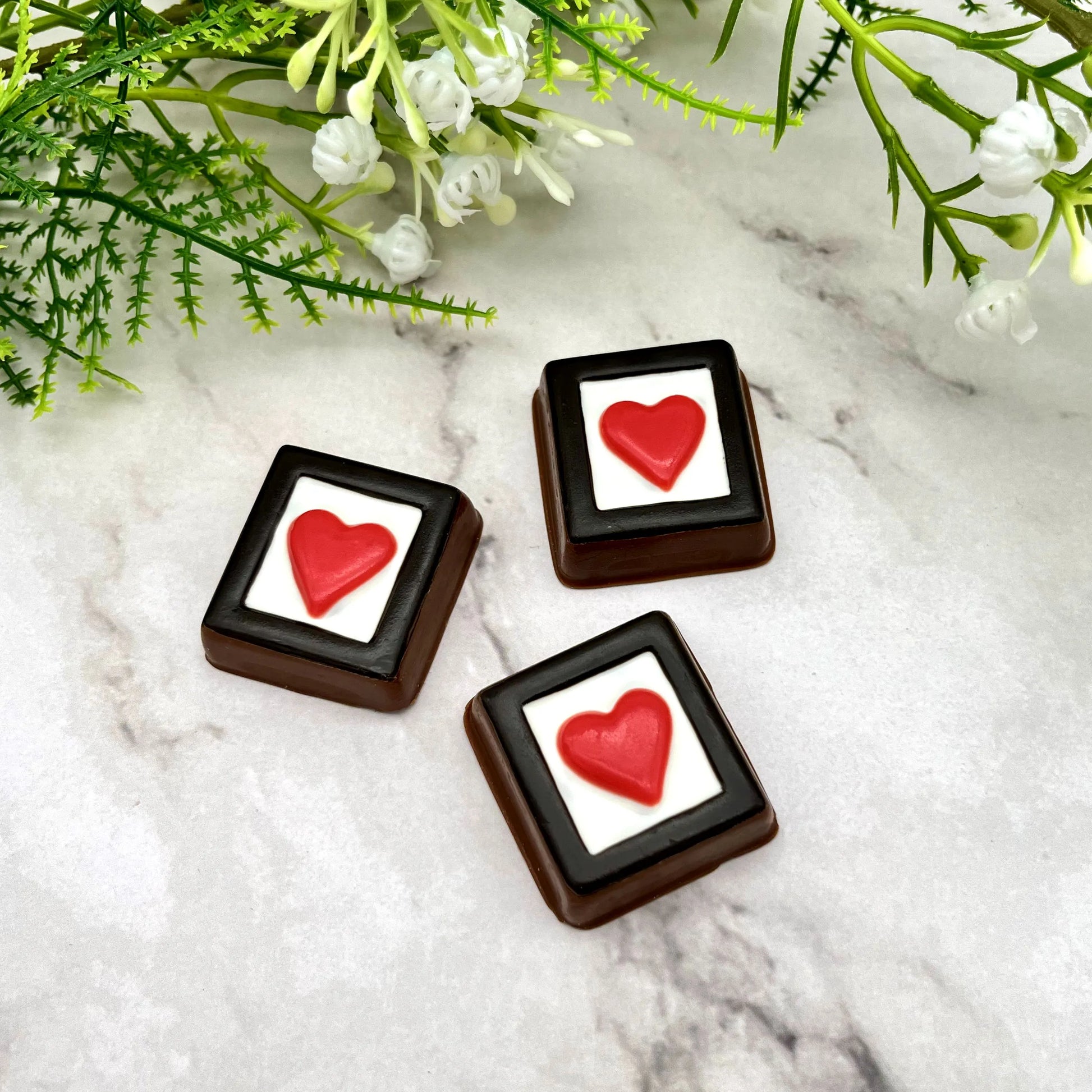 Red heart in a white box, framed in black, made of chocolate. 