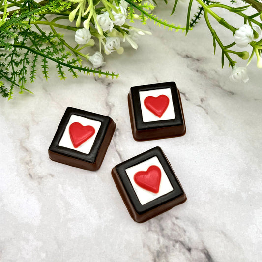 Red heart in a white box, framed in black, made of chocolate. 