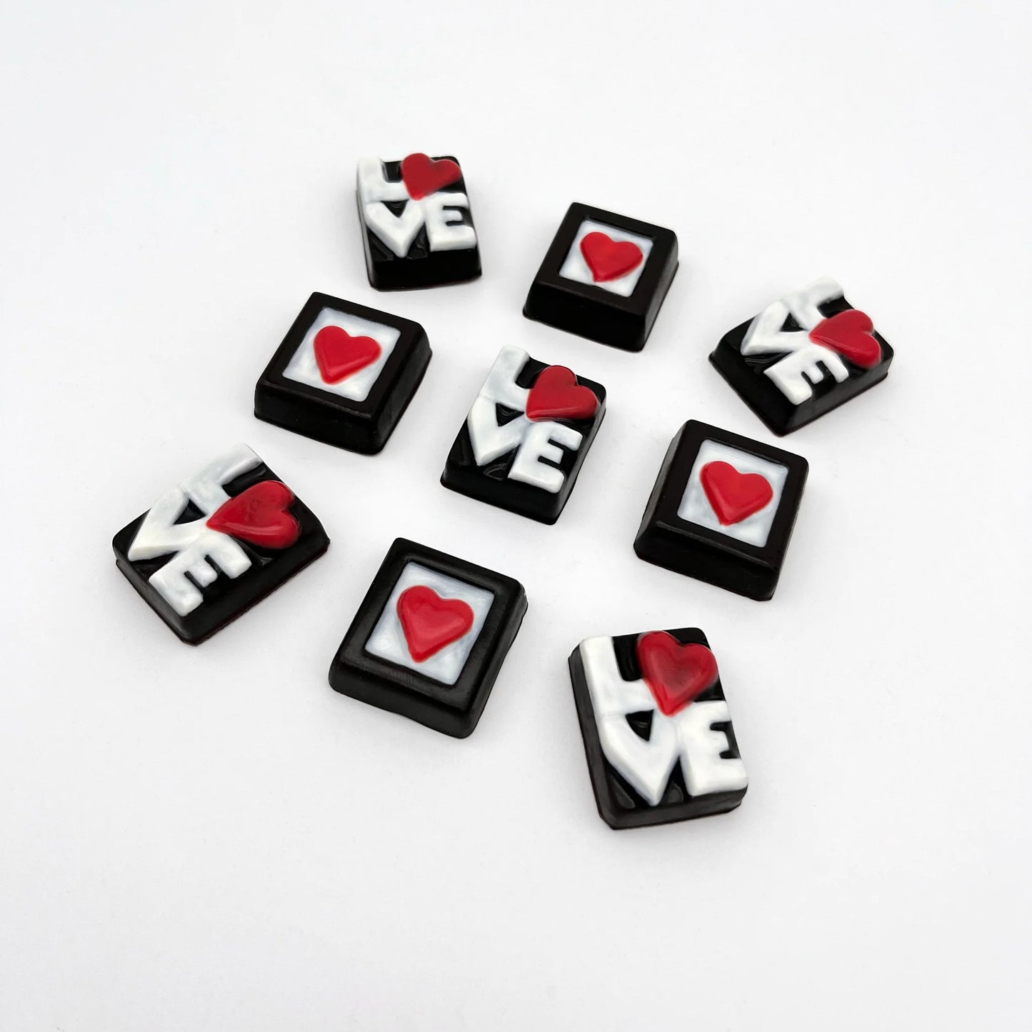 Red heart in a white box, framed in black, made of chocolate. Pictured with chocolate LOVE letters in white, with the O as a red heart, on a black background.