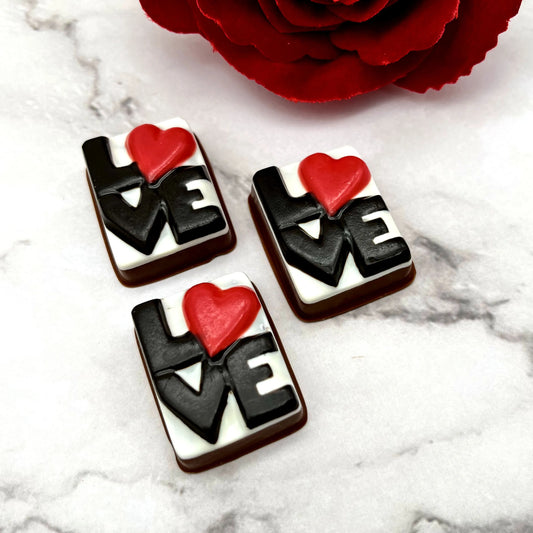 Chocolates with the letters LOVE in white, with the O as a red heart, on a black background.