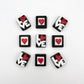 Chocolates with the letters LOVE in white, with the O as a red heart, on a black background. Pictured with chocolates with a red heart in a white box, framed in black.