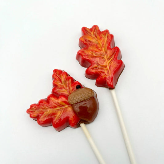 Hand-painted chocolate sucker of realistic-looking brown acorn with two fall-coloured leaves, along with oak leaf sucker.