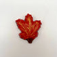Realistic chocolate maple leaf, hand-painted in a blend of yellow, orange and red fall seasonal colours.