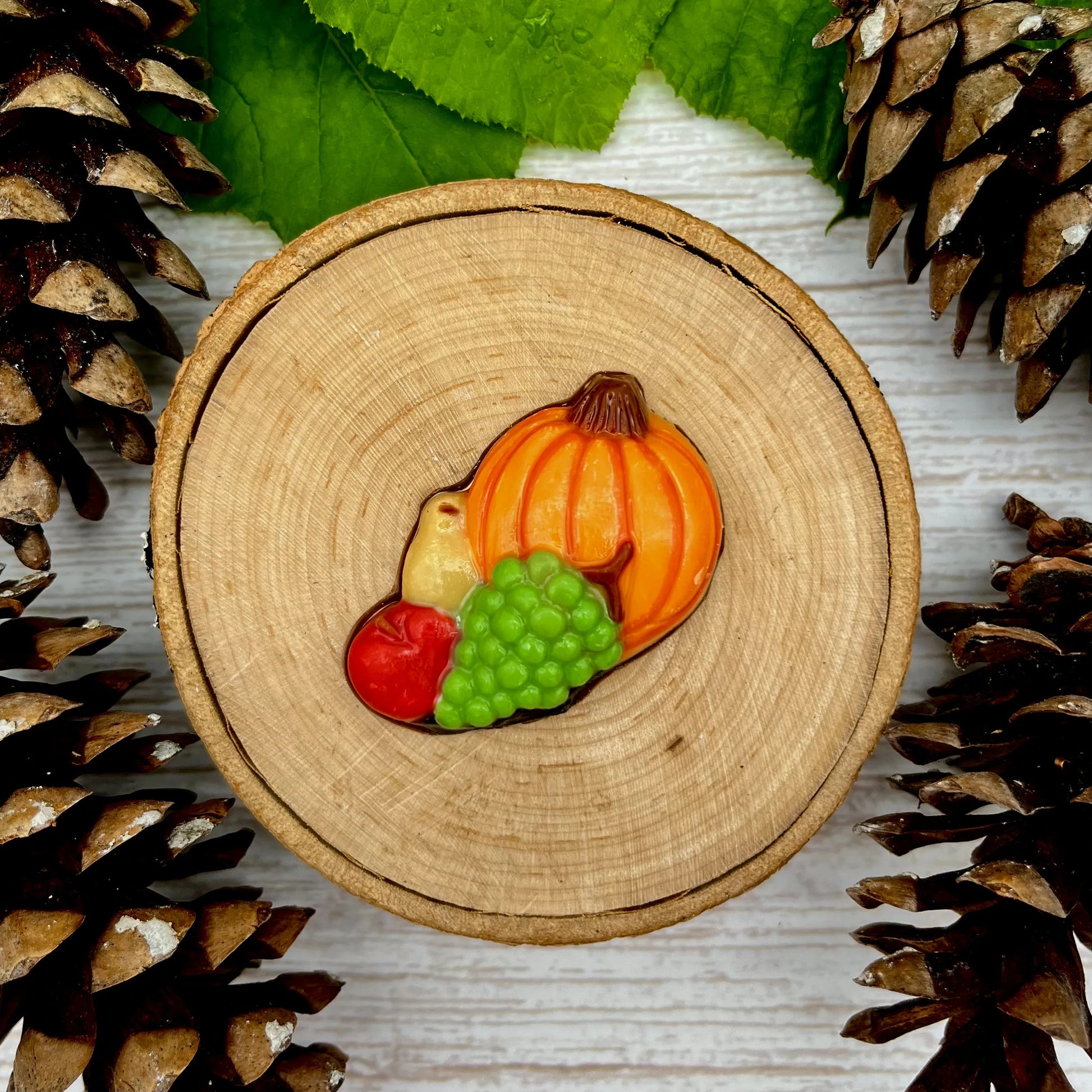 Classic orange pumpkin with green grapes, an apple and pear in front of them. Made from chocolate.