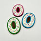 Three colourful number '0' chocolates, hand-painted with multi-colour dots and sprinkles. Displayed on a white background.