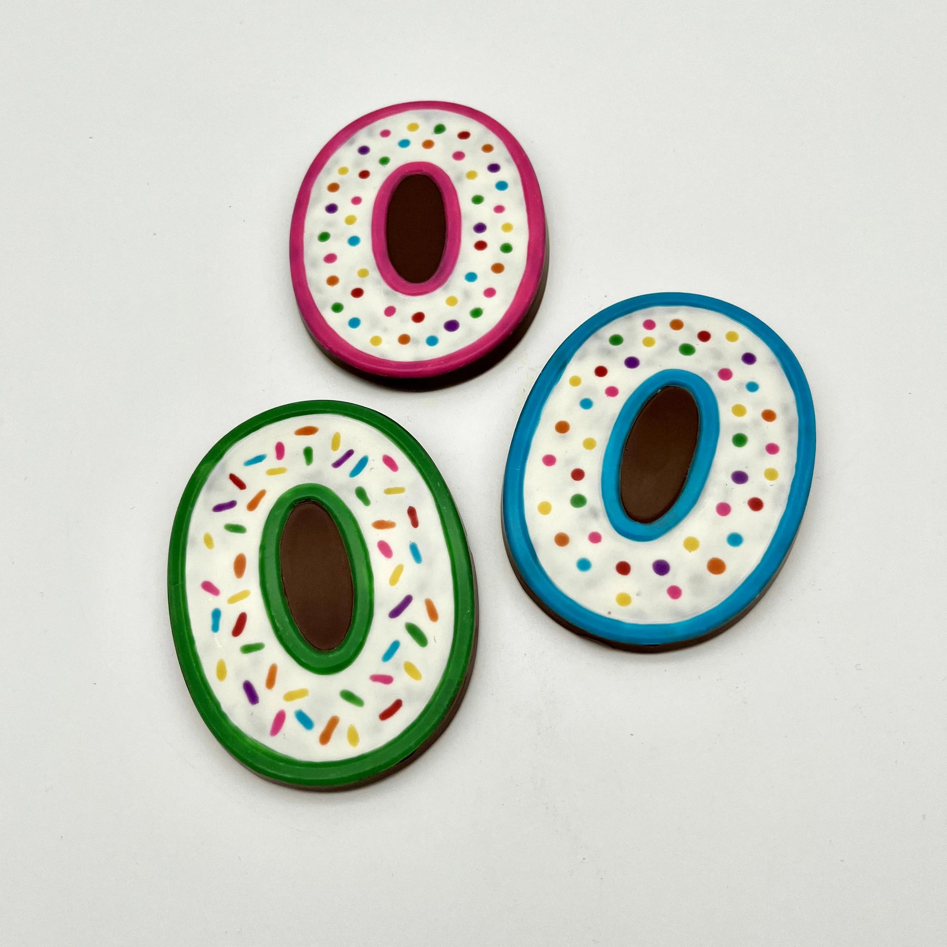 Three colourful number '0' chocolates, hand-painted with multi-colour dots and sprinkles. Displayed on a white background.