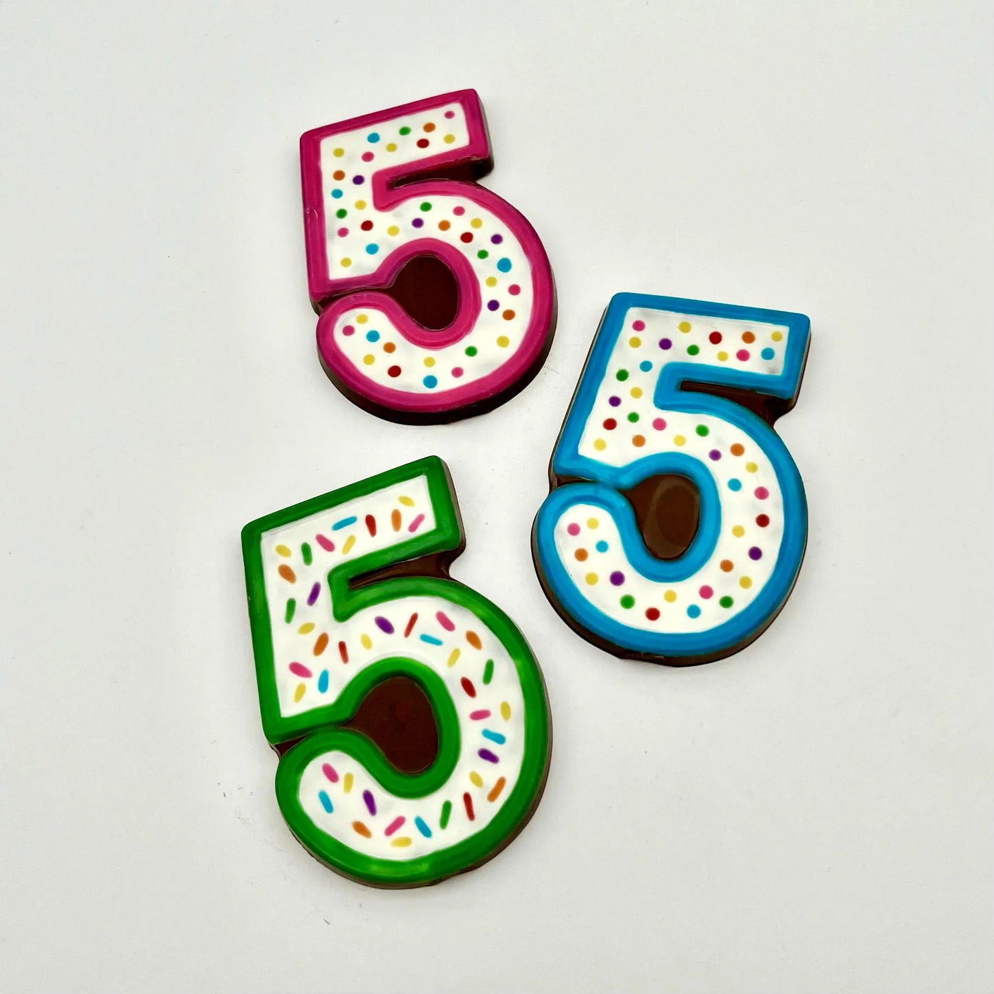 Three colourful number '5' chocolates, hand-painted with multi-colour dots and sprinkles. Displayed on a white background.