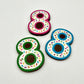 Three colourful number '8' chocolates, hand-painted with multi-colour dots and sprinkles. Displayed on a white background.